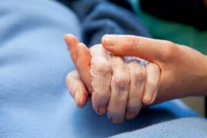A person holding an elderly persons hand